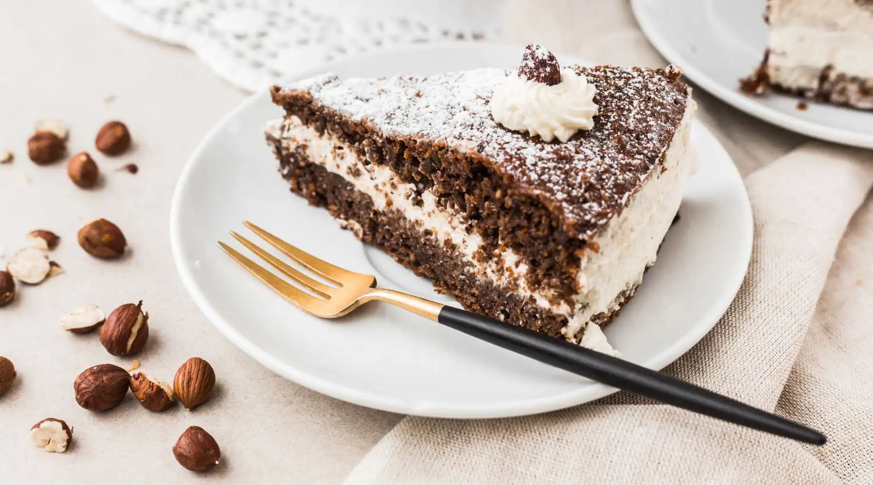 Ein Stück Haselnusstorte ohne Mehl nach dem Rezept von Oma Helga von Kuchentratsch auf einem Teller mit Kuchengabel