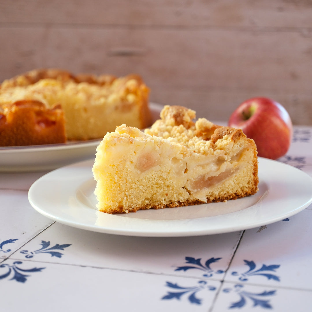 Ein Stück vom Apfelstreuselkuchen von Kuchentratsch mit Kuchen und Apfel im Hintergund