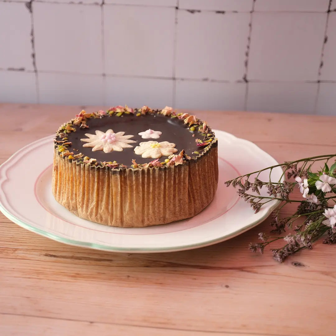 Der Frühlingskuchen von den Omas von Kuchentratsch mit Mürbteig Blumen verziert auf einem Holztisch mit Blumen.