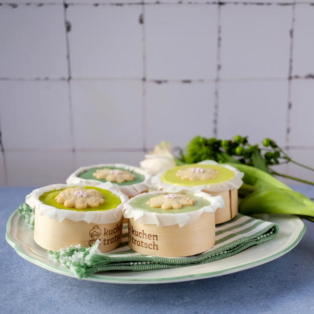 Die Frühlingstörtchen Apfel Karotte von den Kuchentratsch Omas im Viererset auf einem Teller mit Blumen.