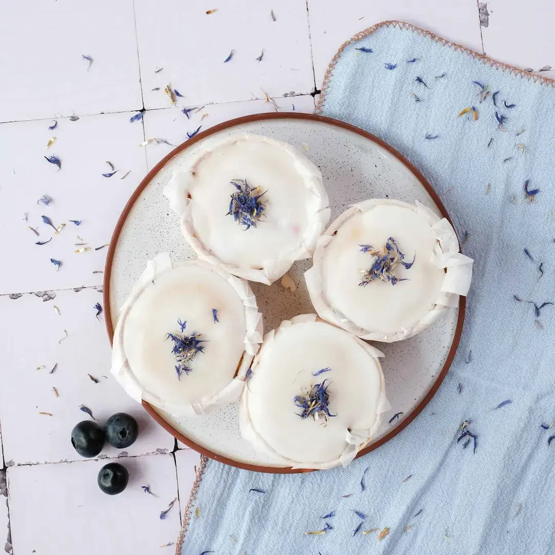 Heidelbeer Muffins von Oma Hildegard fotografiert von Oben auf weißen Fließen mit Tischdecke und Blütendeko