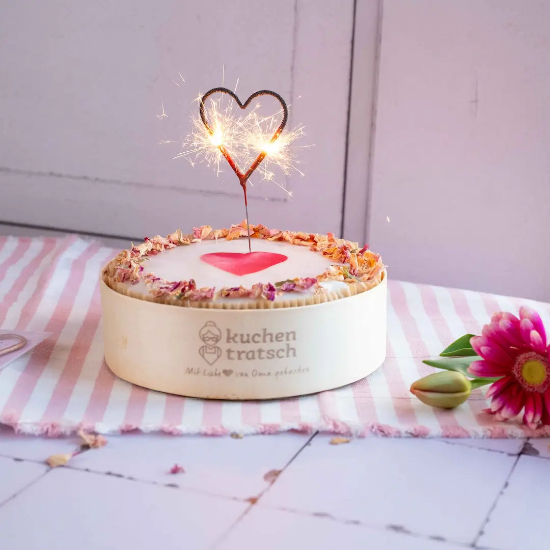Unser Herzkuchen Karotte mit angezündeter Herzwunderkerze auf Tischdecke von Kuchentratsch