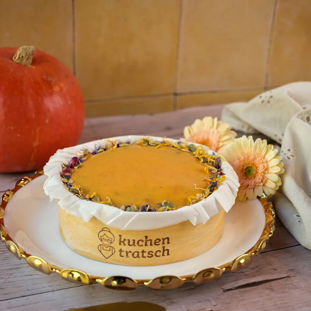 Herbstlicher Pumpkin-Spice-Kuchen mit Kurkuma-Glasur von Kuchentratsch auf einem Teller mit einem Kürbis im Hintergrund