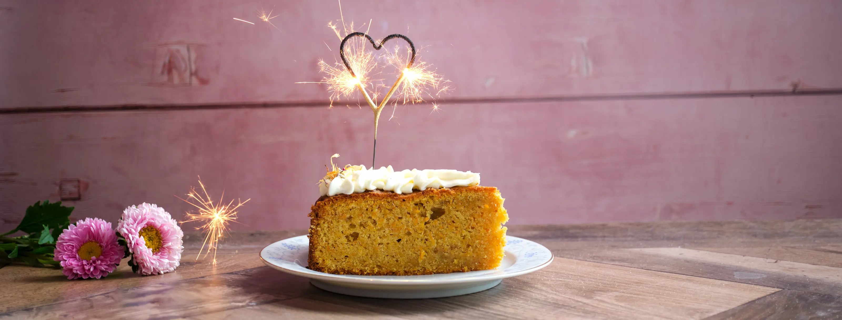 Ein Stück von dem Karottenkuchen von Kuchentratsch mit einer brennenden Herzwunderkerze