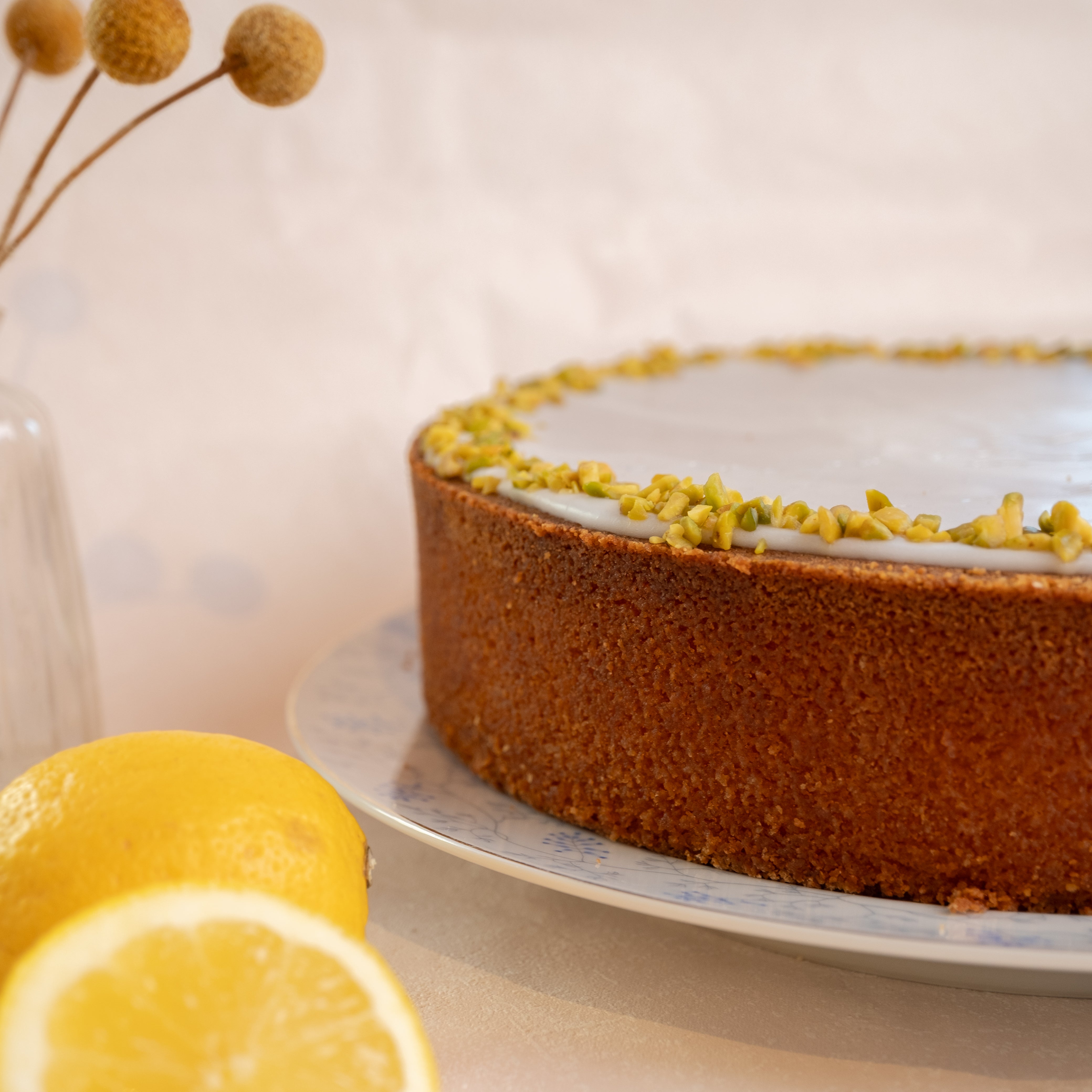 Der große Zitronenkuchen von Kuchentratsch von der Seite mit Zitronen im Vordergrund