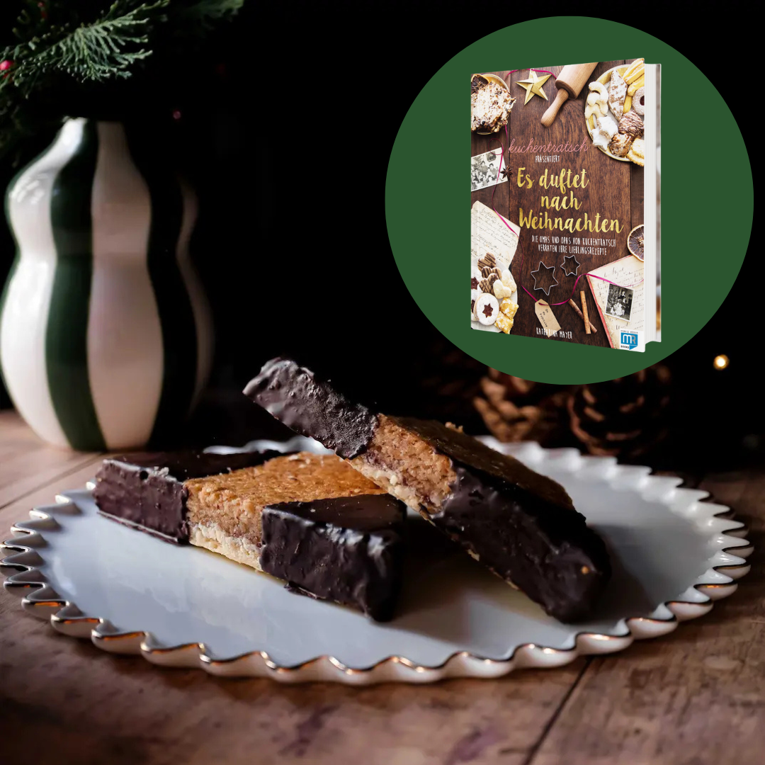 Zwei saftige Nussecken auf Teller mit dem Kuchentratsch Weihnachtsbackbuch im Hintergrund