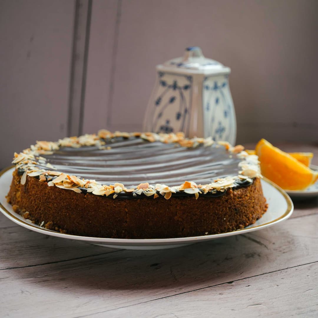 Orangen Mandel Tarte von Kuchentratsch auf Holztisch mit Kaffeekanne und Orangen 