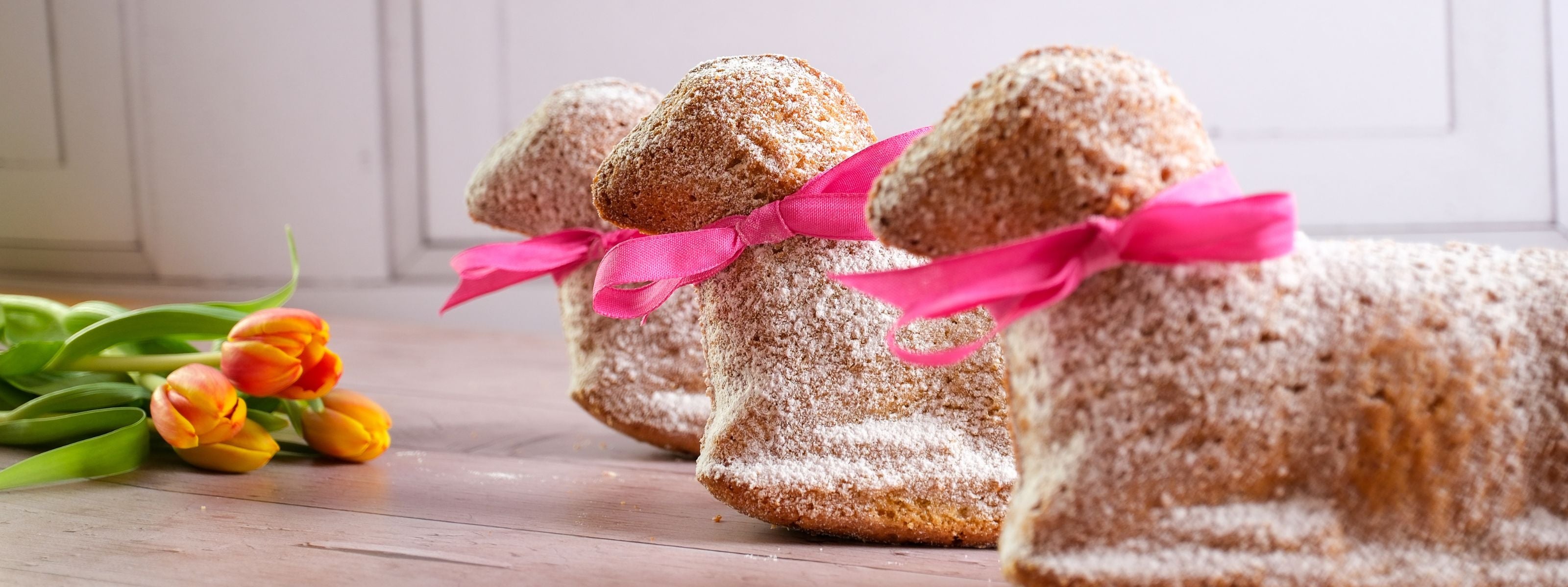 Unser Osterlamm von Kuchentratsch, drei nebeneinder mit Tulpen auf einem Holztisch
