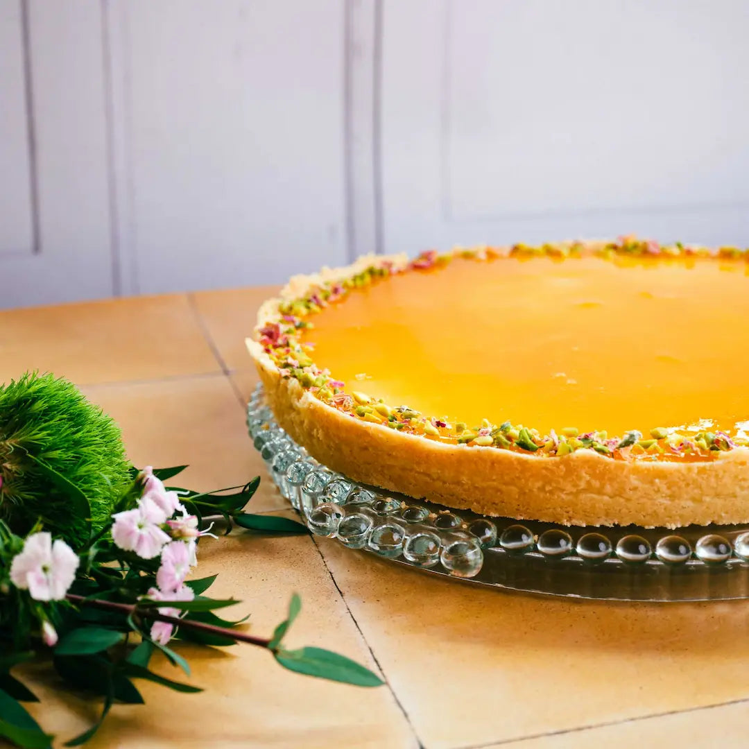 Zitronen Oassionsfrucht Tarte von Kuchentratsch auf Tisch mit Blumen im Vordergrund